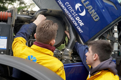 Two agricultural engineering apprentices looking at a New Holland tractor engine